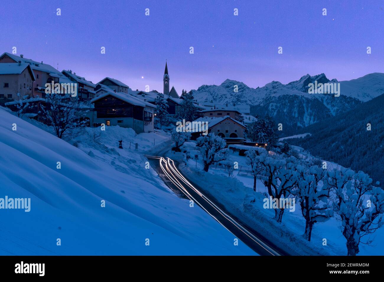 Village enneigé de Guarda éclairé par des feux de circulation pendant un crépuscule bleu d'hiver, Basse Engadine, canton de Graubunden, Suisse, Europe Banque D'Images