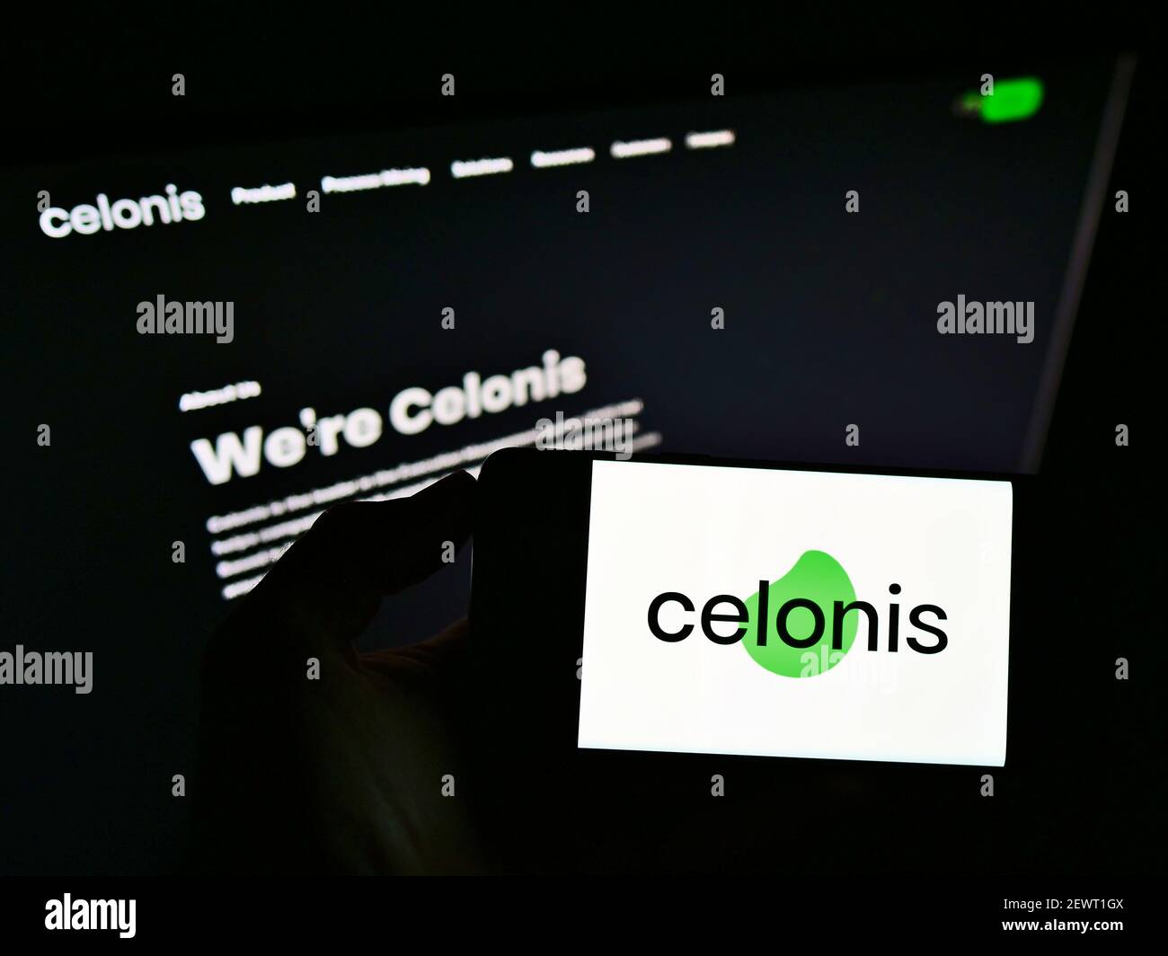 Vue à grand angle de la personne tenant le téléphone portable avec le logo de la société de logiciel allemande Celonis se sur l'écran en face de la page Web. Mise au point sur l'affichage du téléphone. Banque D'Images