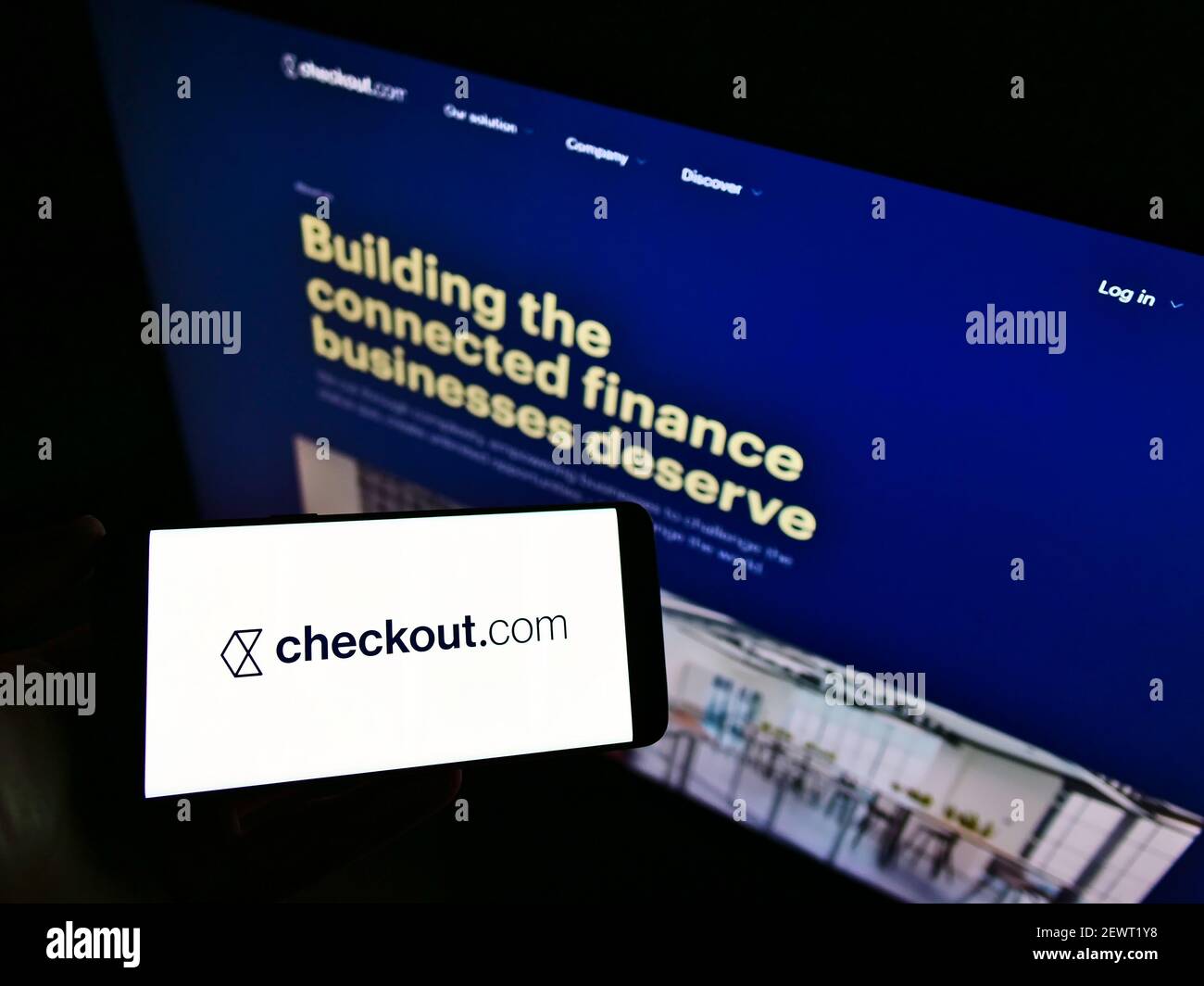 Personne tenant un smartphone avec le logo de la société britannique fintech Checkout.com (services de paiement) à l'écran devant le site Web. Mise au point sur l'affichage du téléphone. Banque D'Images