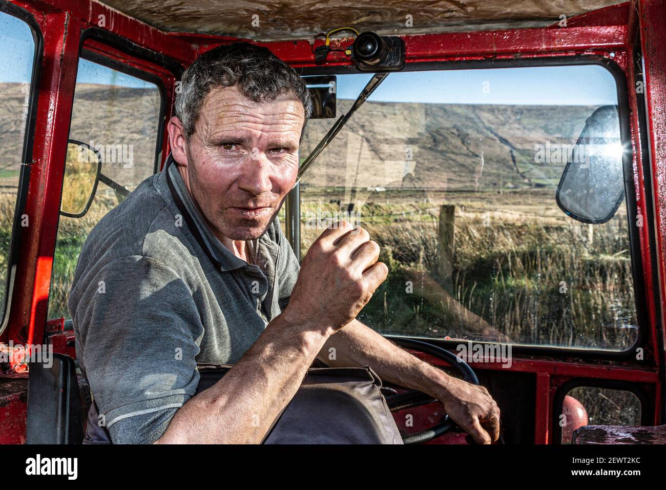 Agriculteur irlandais de race masculine dans le tracteur rouge Massey Ferguson 35X, comté de Kerry, Irlande Banque D'Images