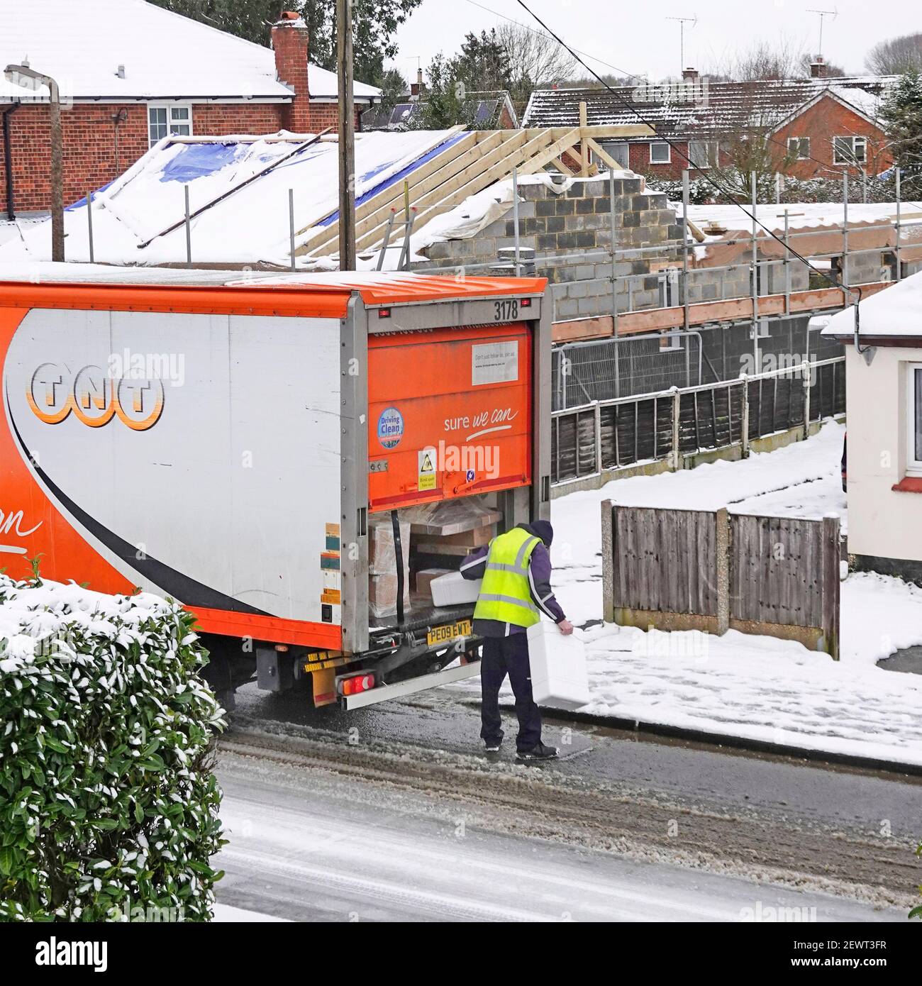 Activité de livraison de colis TNT par temps froid et neige glacée conducteur de camion en blouson haute visibilité pour la livraison de colis Icy Road Angleterre Royaume-Uni Banque D'Images