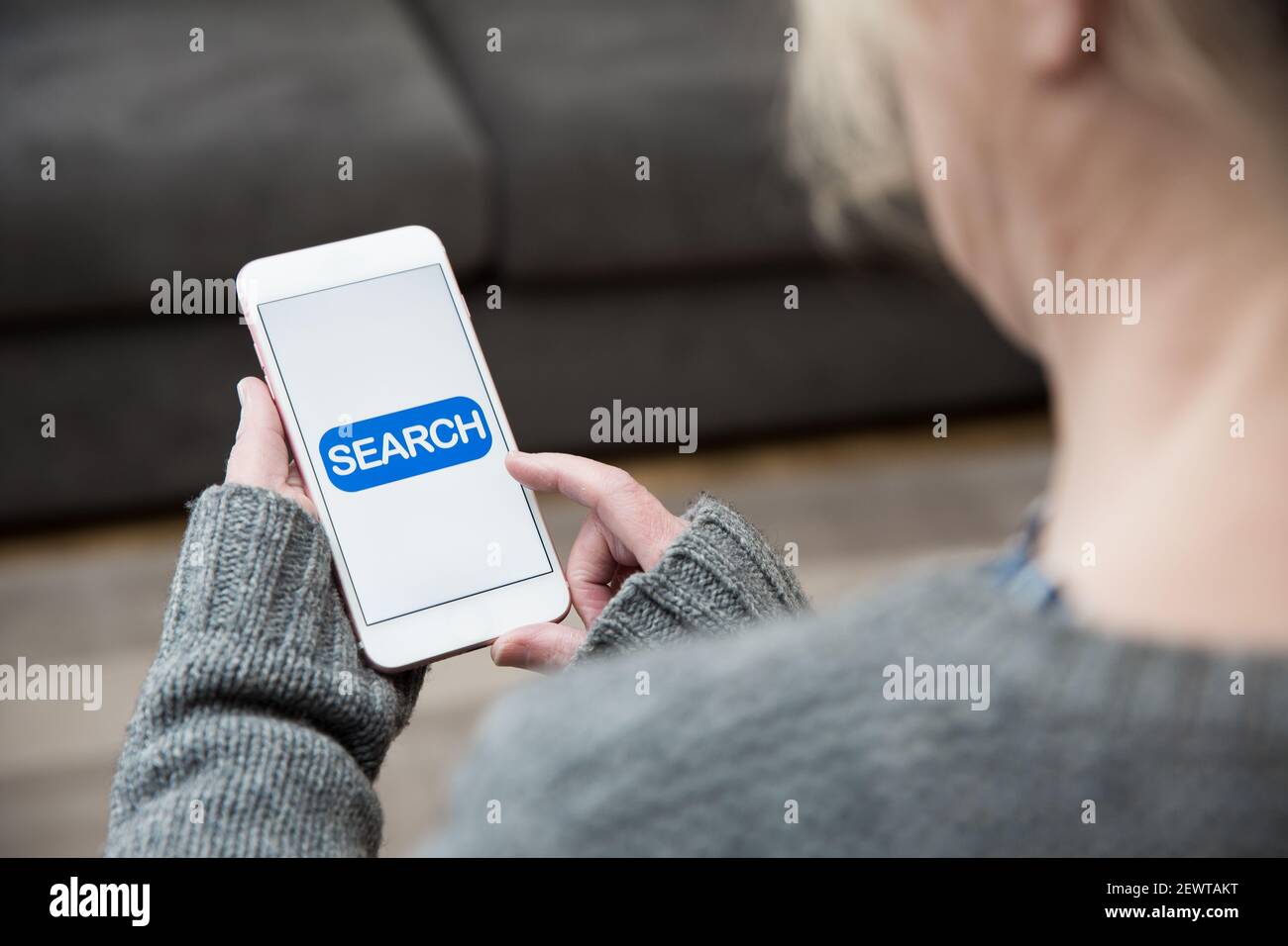 Une femme touchant une icône de recherche sur son téléphone mobile tout en recherchant des informations sur le contenu en ligne Banque D'Images