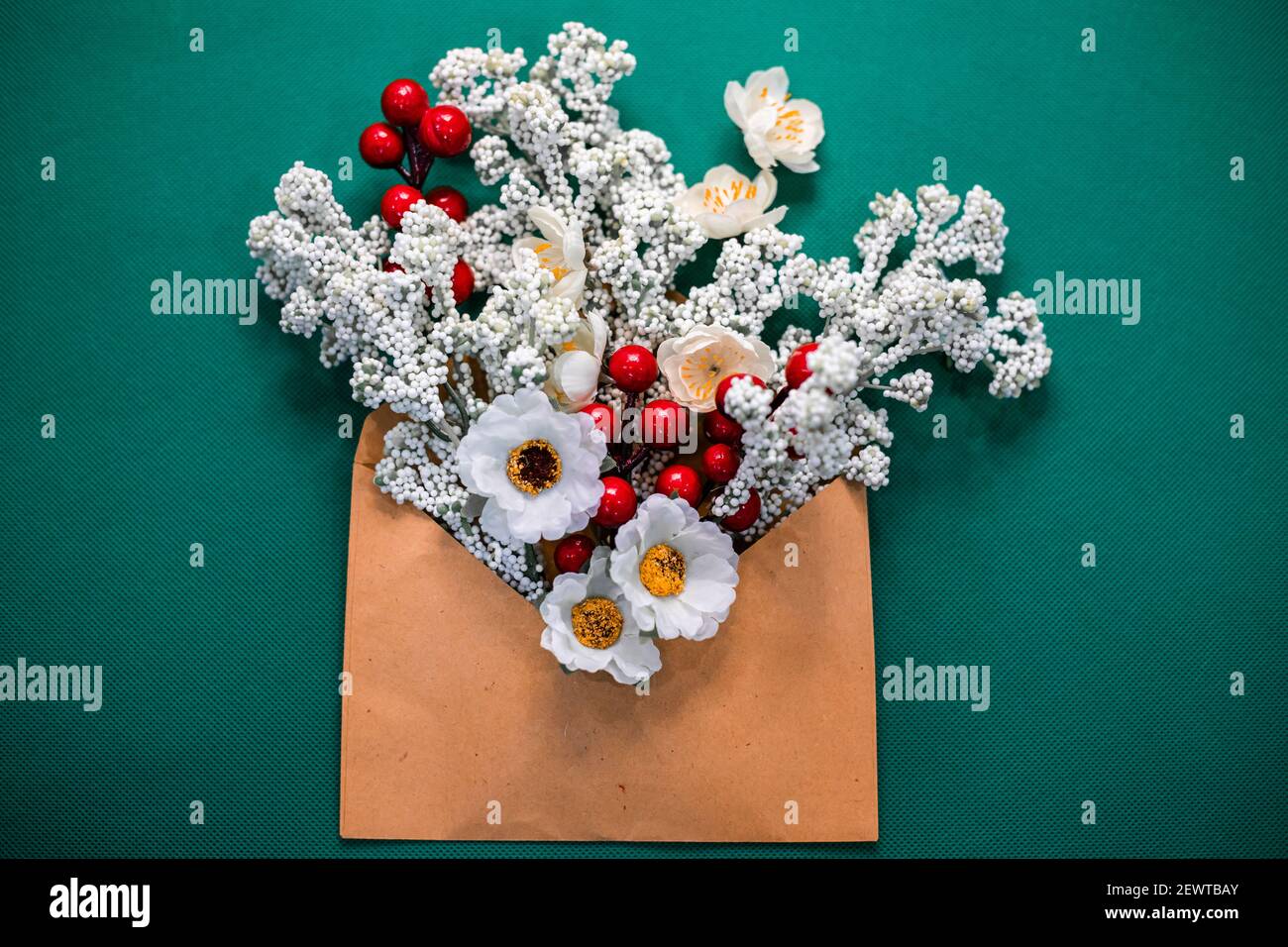 Fleurs dans une enveloppe au début du printemps. Fleurs faites à la main, enveloppe en papier et fond vert dans l'atelier Banque D'Images