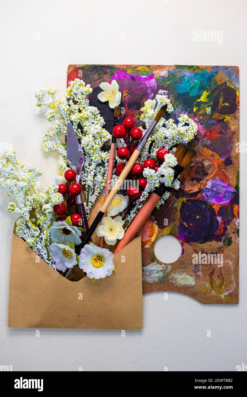 La créativité dans un atelier de peinture de femme. Outils de peinture, pinceaux, fleurs et une palette de couleurs magnifiques Banque D'Images