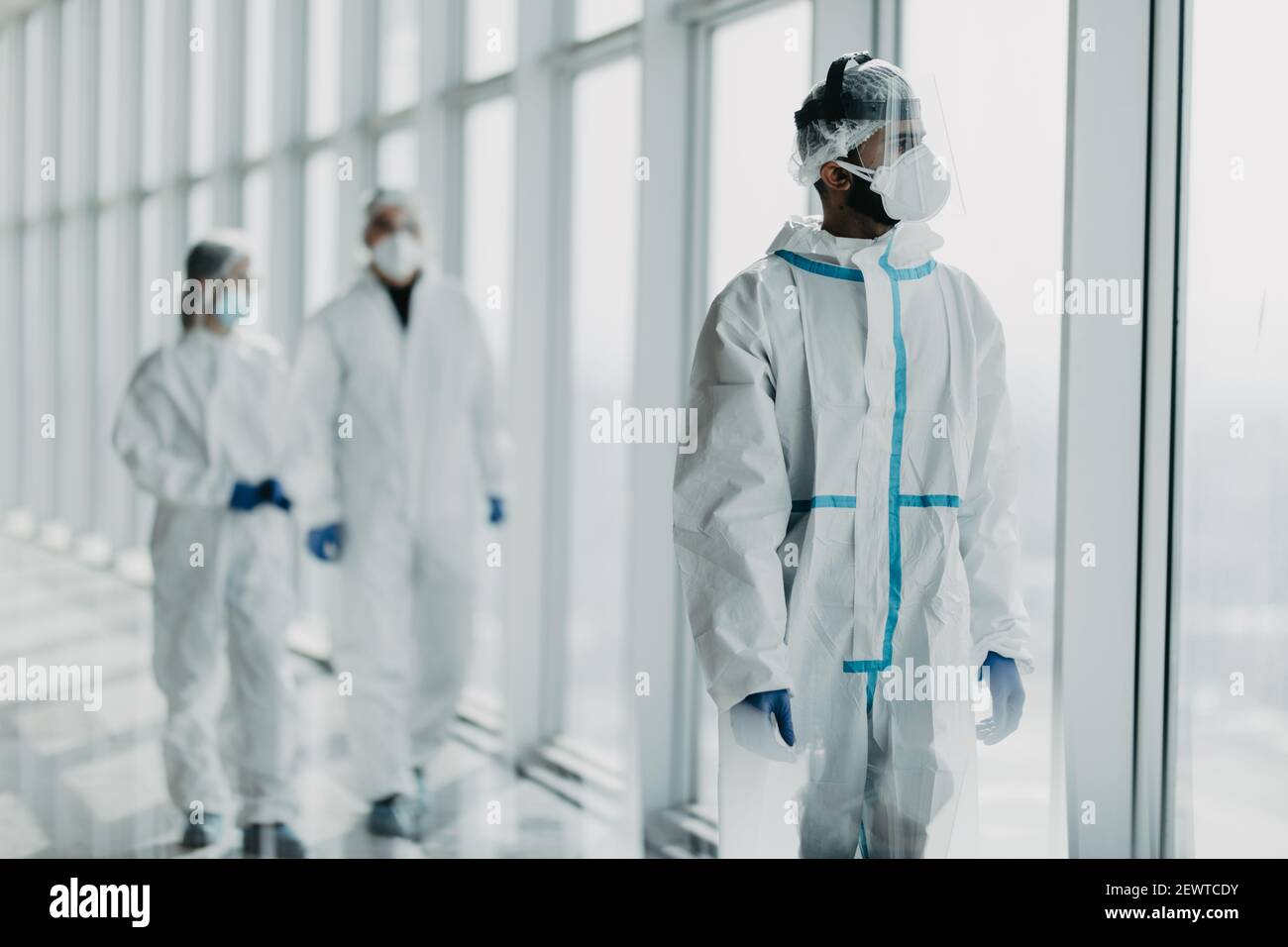 Les désinfecteurs ou les médecins marchent en uniforme de protection dans  le couloir de l'hôpital. Des scientifiques travaillant dans des combinaisons  de biohazmat se promo le long de l'halw du laboratoire chimique