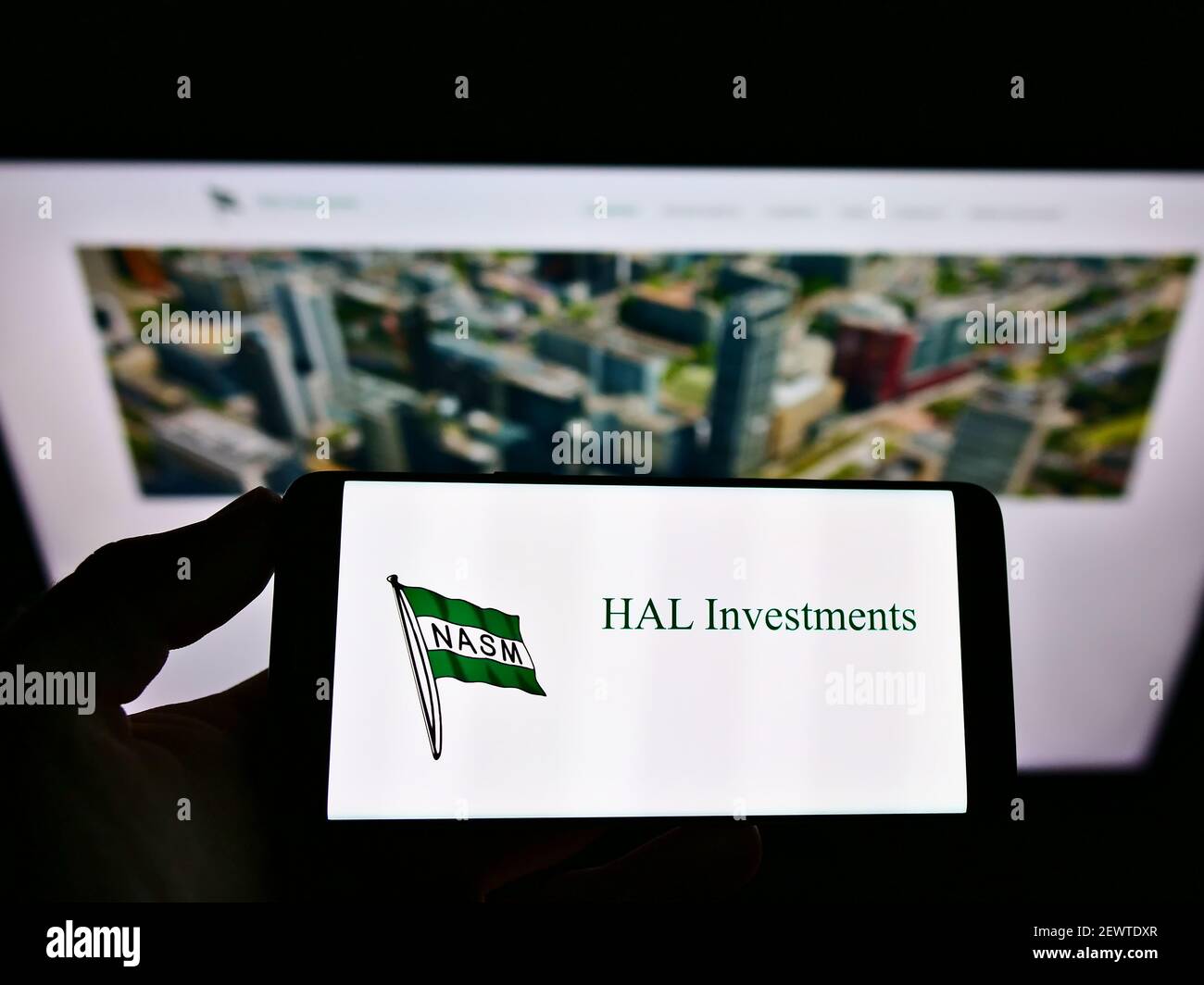 Vue en grand angle de la personne qui tient un smartphone avec le logo d'entreprise de la société HAL Holding N.V. à l'écran en face de la page Web. Mise au point sur l'affichage du téléphone. Banque D'Images