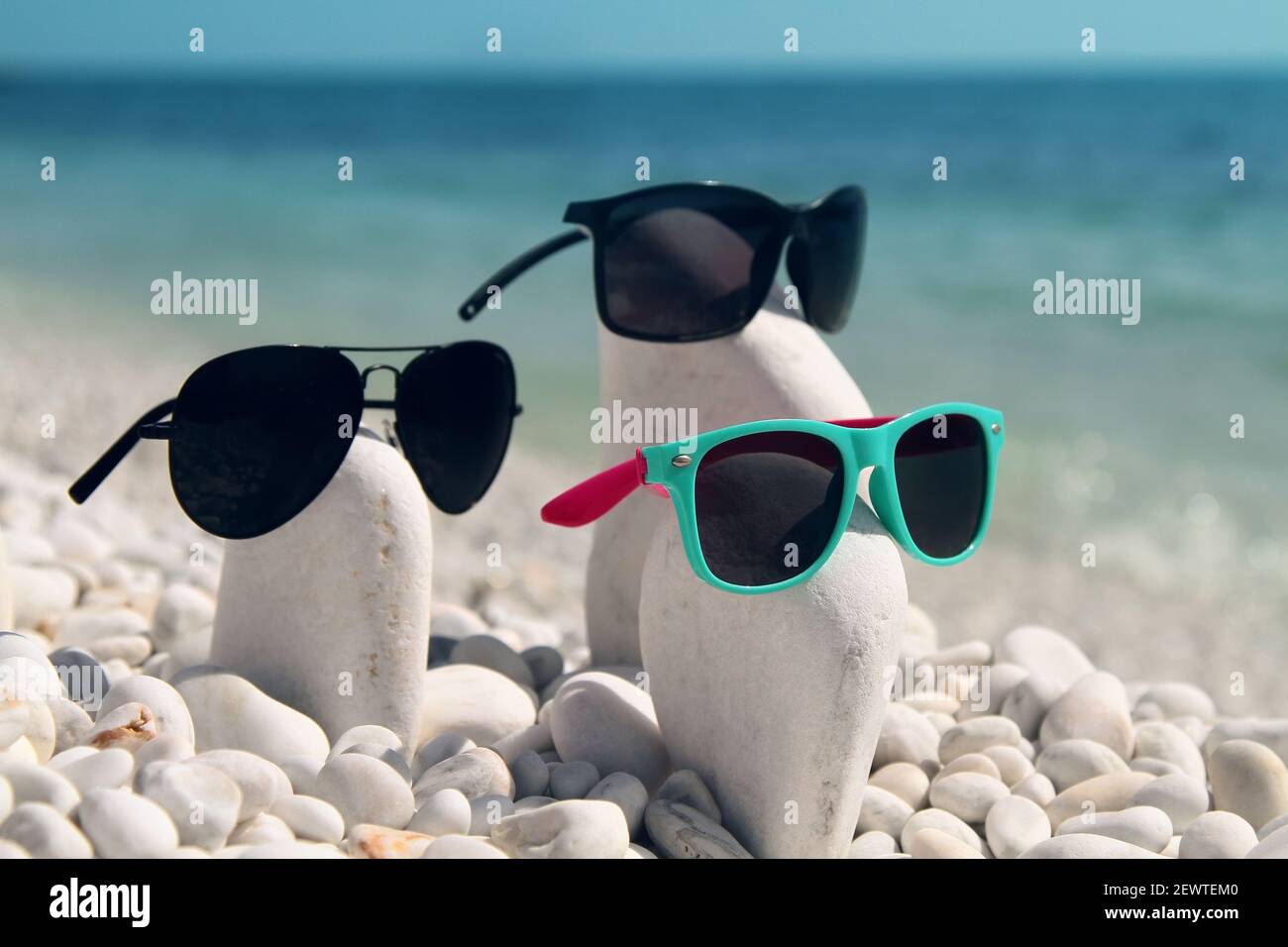 Composition estivale amusante de pierres de galet blanc et de lunettes de soleil imitant les visages des gens et créant une « famille ». Marina di Pisa. Italie. Banque D'Images
