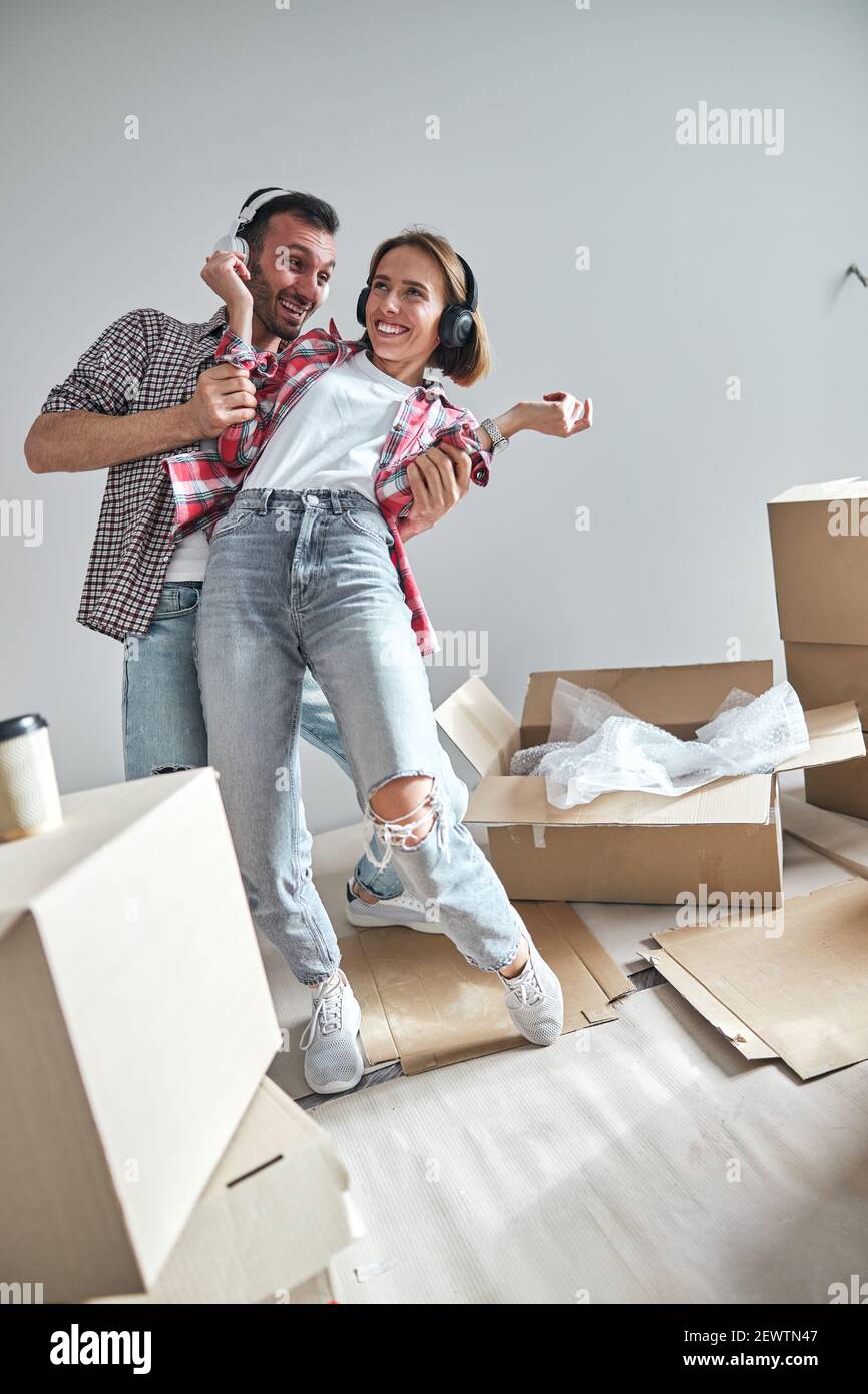 Une femme joyeuse et son mari dansent dans leur nouvel appartement Banque D'Images