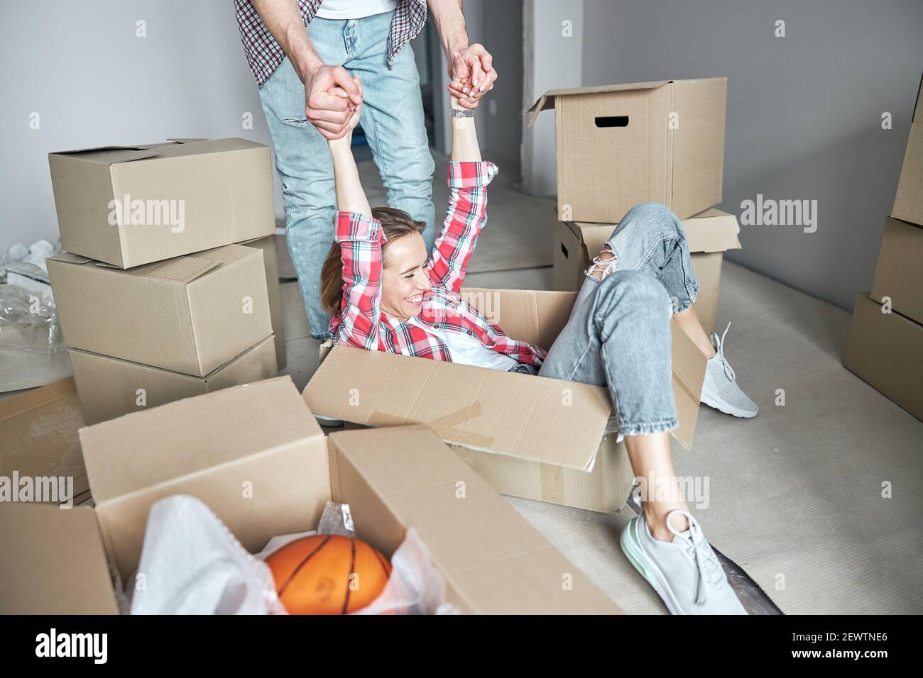 Femme allongé dans une boîte en carton étant relevée à pieds Banque D'Images
