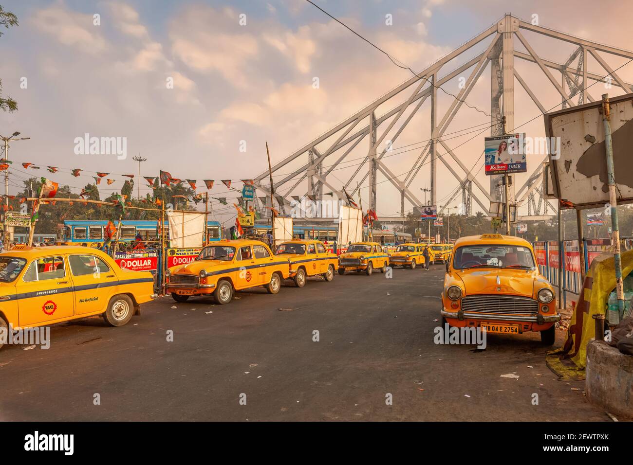 Des taxis jaunes à la station de taxis attendent les navetteurs près du pont de Howrah à Kolkata, en Inde, au lever du soleil Banque D'Images
