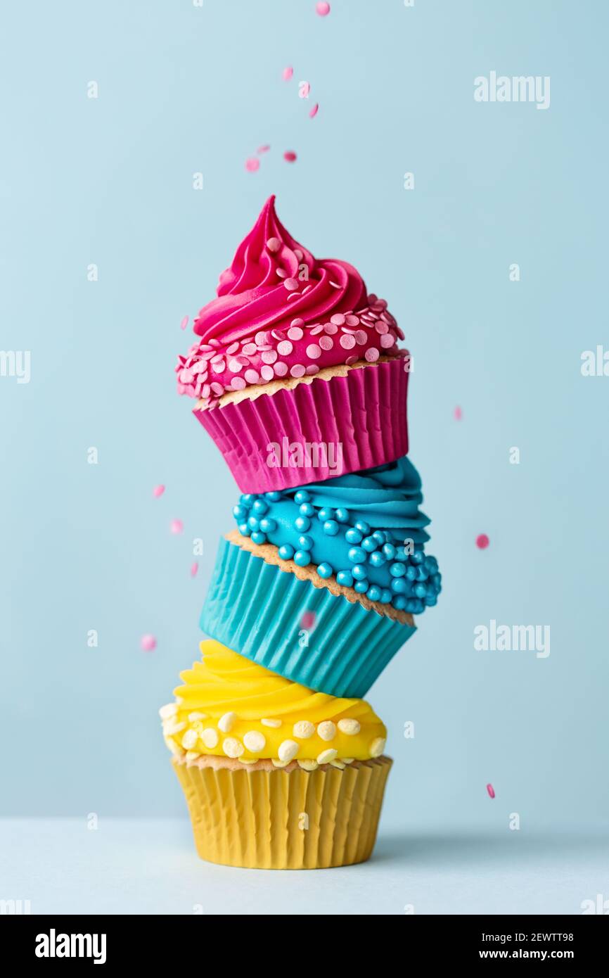 Pile de trois cupcakes colorés avec des arrosettes tombantes Banque D'Images