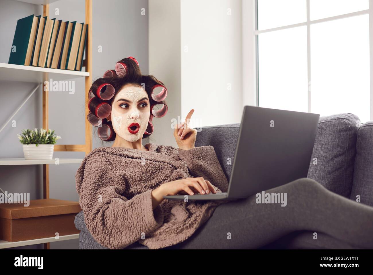 Femme dans les curlers et masque de visage de navigation Internet et d'apprentissage des idées et des hacks incroyables Banque D'Images
