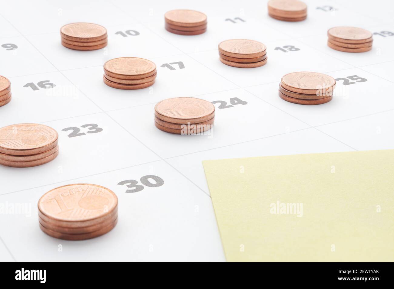 Prévoyez économiser de l'argent pour la gestion du budget. Coût de la vie. Rapport mensuel. Note en papier jaune vide dans le calendrier du dernier jour du mois avec des piles de pièces en euros Banque D'Images