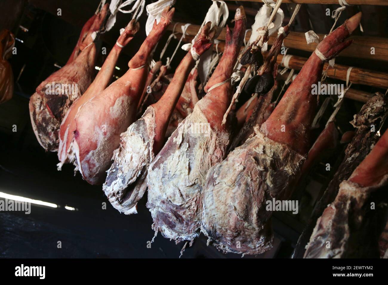 Des jambes fumées de jambon dans un fumoir. Jambon entier suspendu au plafond de la ferme. Guérison et séchage des jambons des porcs ibériques Banque D'Images