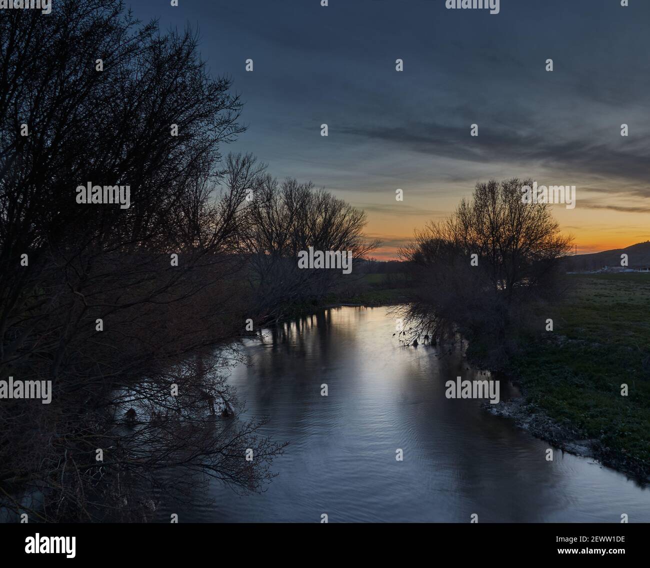 Impressionnant coucher de soleil sur la rivière Manzanares avec la végétation le rivage et les lumières du coucher du soleil se reflètent dans ses eaux Banque D'Images