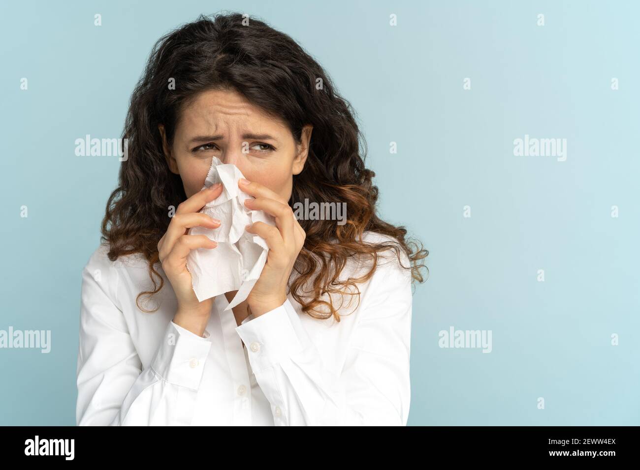 Employée de bureau femme en blouse blanche avec un nez soufflant de tissu, souffrant de rhinite. Studio. Banque D'Images