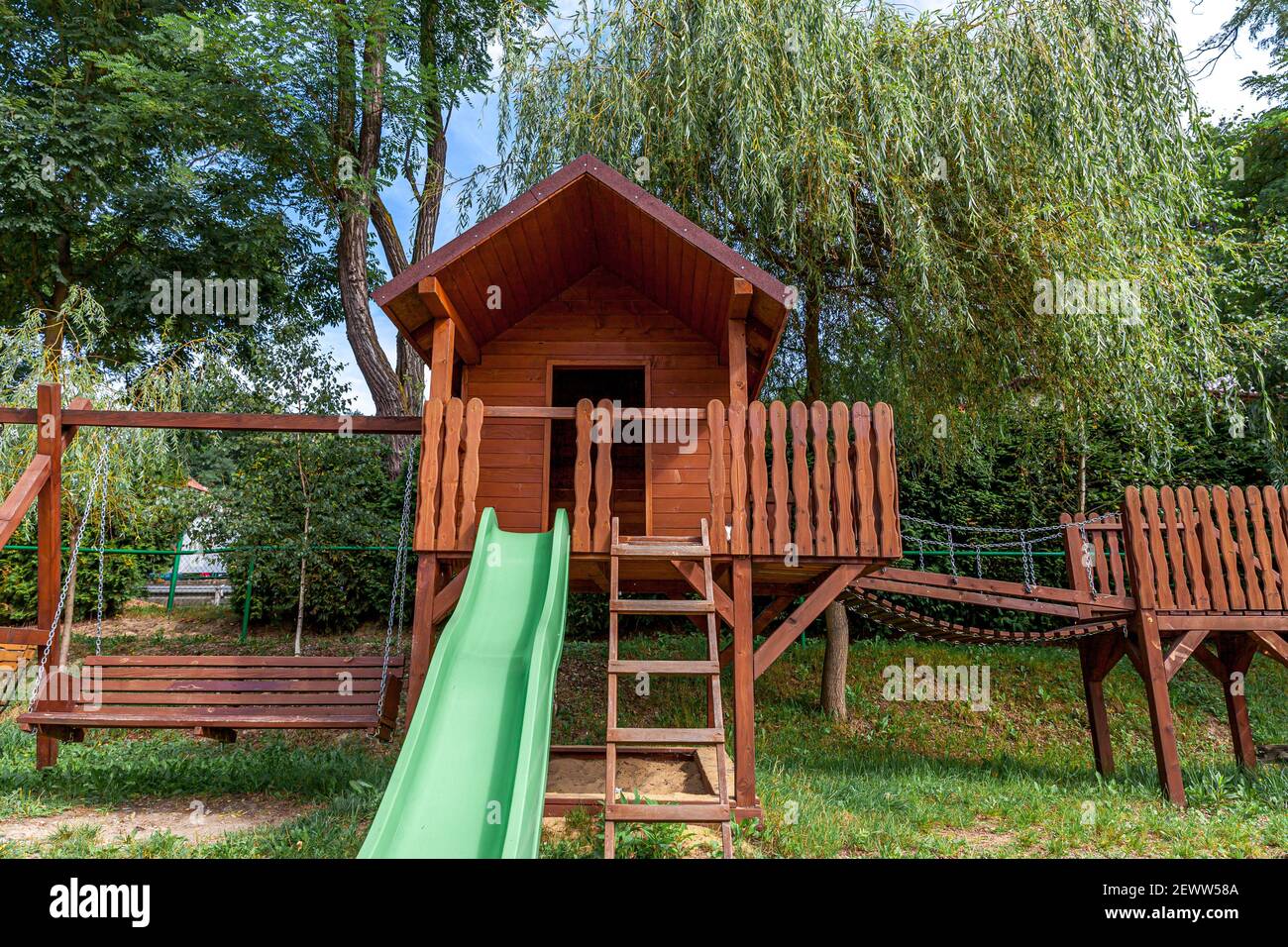 Aire de jeux en bois moderne et vide située sur une cour verte dans le parc public en été. Terrain de jeu amusant pour les enfants. Activités d'exercice en milieu urbain pour les enfants en plein air. Concept d'enfance de quartier Banque D'Images