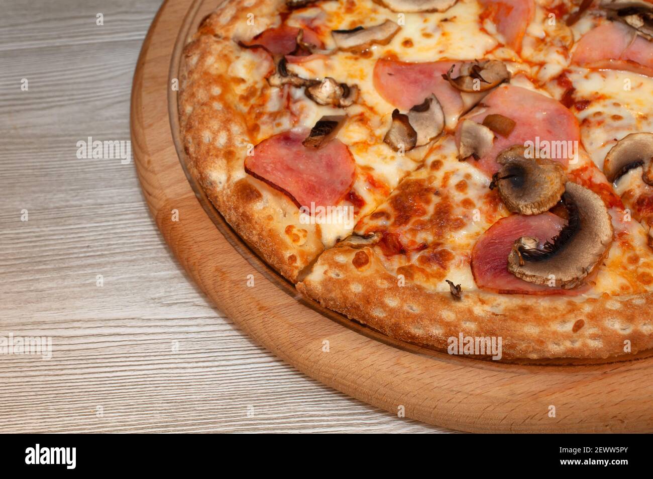 Pizza au jambon, aux champignons et au fromage sur une planche Banque D'Images