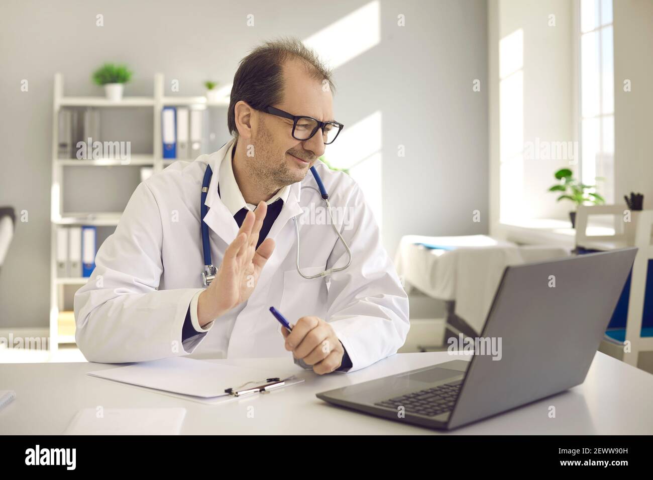 Un médecin heureux vous saluant sur un ordinateur portable saluant le patient en ligne consultation vidéo Banque D'Images