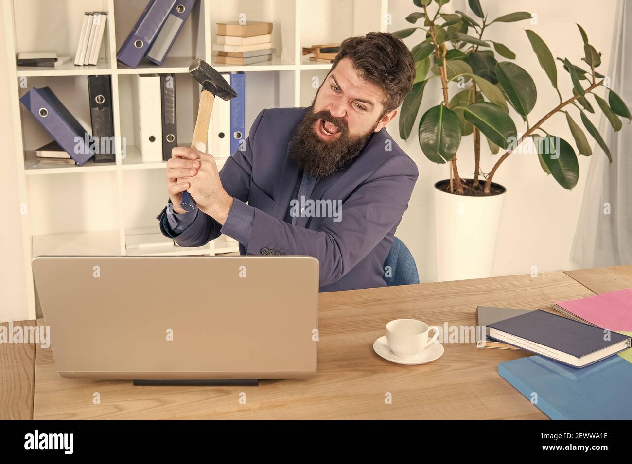 Crier. Résoudre certains problèmes d'affaires. Ordinateur est à la traîne. Homme d'affaires ou Manager en colère avec un marteau à traîner. Homme d'affaires agressif au bureau. Raisons du retard de l'ordinateur. Routine de bureau de haine. Banque D'Images