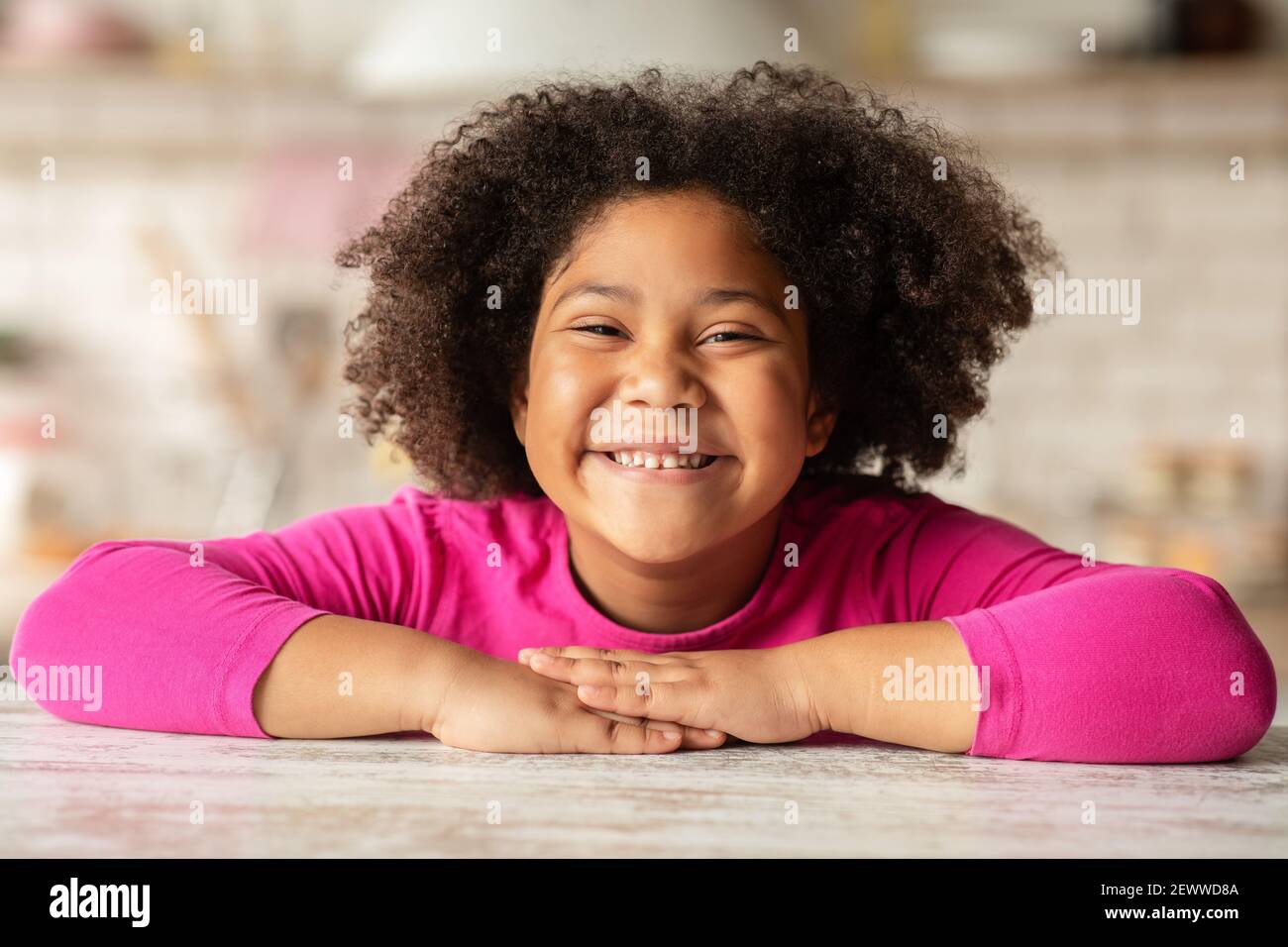 Enfant heureux. Portrait de petite fille noire joyeuse assise à la table Banque D'Images