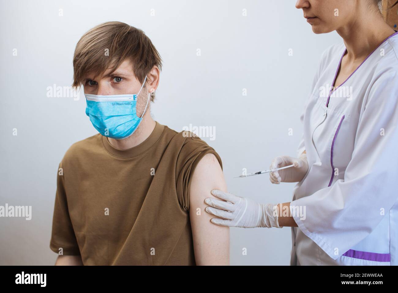 Un homme reçoit le vaccin Covid-19. Gros plan médecin faisant l'injection au patient dans le masque médical. Seringue de vaccin contre le coronavirus. L'homme reçoit la vaccination de jab Banque D'Images