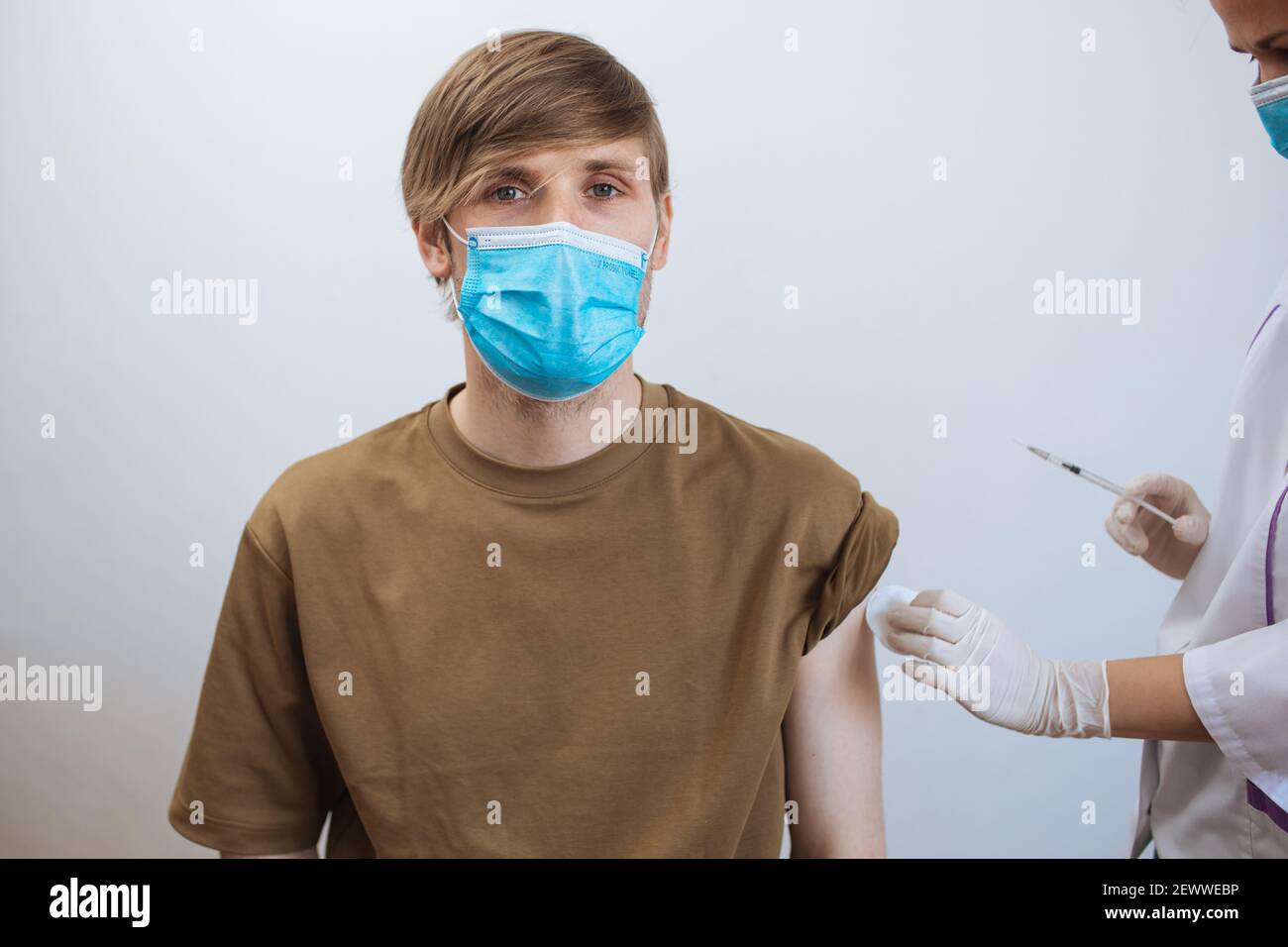 Un homme reçoit le vaccin Covid-19. Gros plan médecin faisant l'injection au patient dans le masque médical. Seringue de vaccin contre le coronavirus. L'homme reçoit la vaccination de jab Banque D'Images