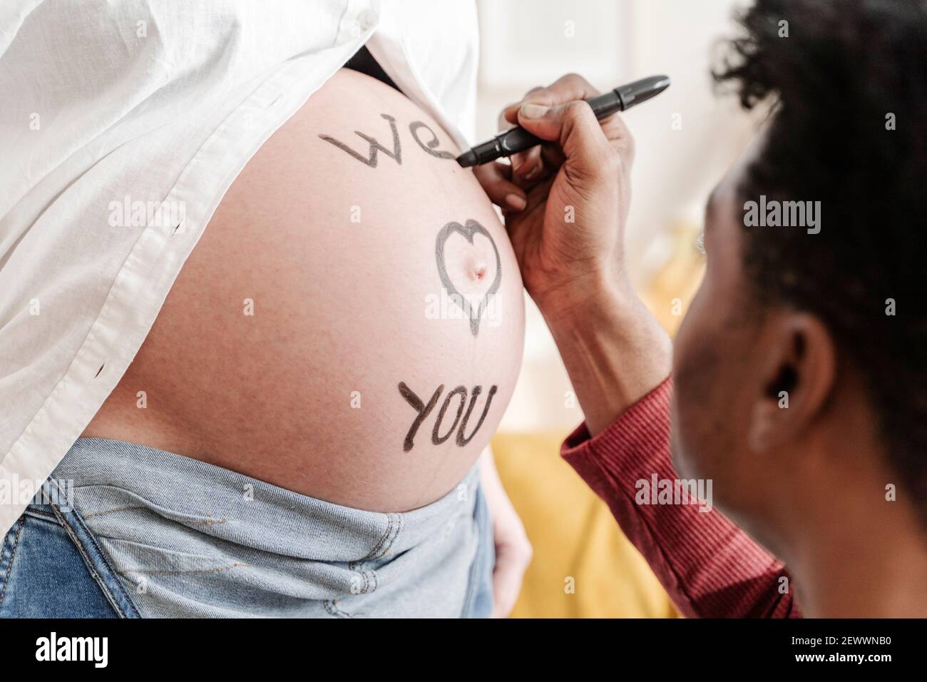 Mari dessin de l'expression nous vous aimons sur le ventre de sa femme enceinte. Concept de planification familiale Banque D'Images