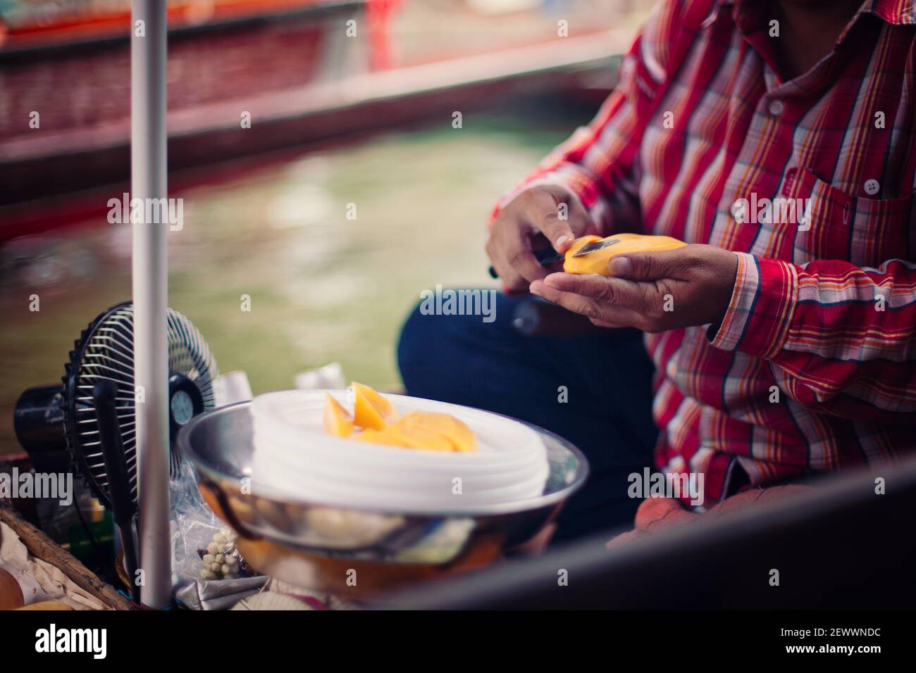 Femme coupant de la mangue au marché flottant en Thaïlande. Banque D'Images