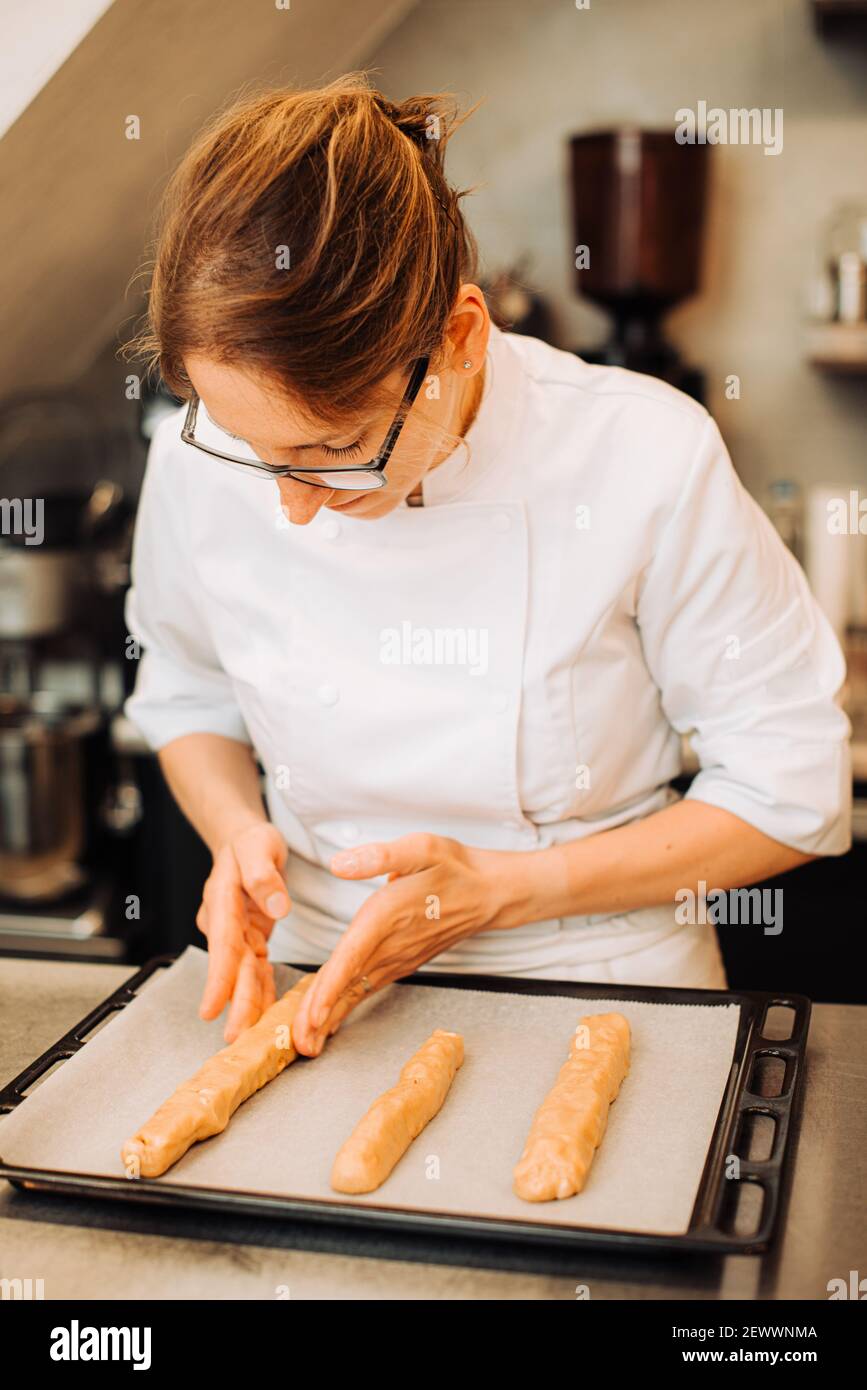 Femme chef mettant de la pâte sur plateau pour cuire des biscuits Banque D'Images