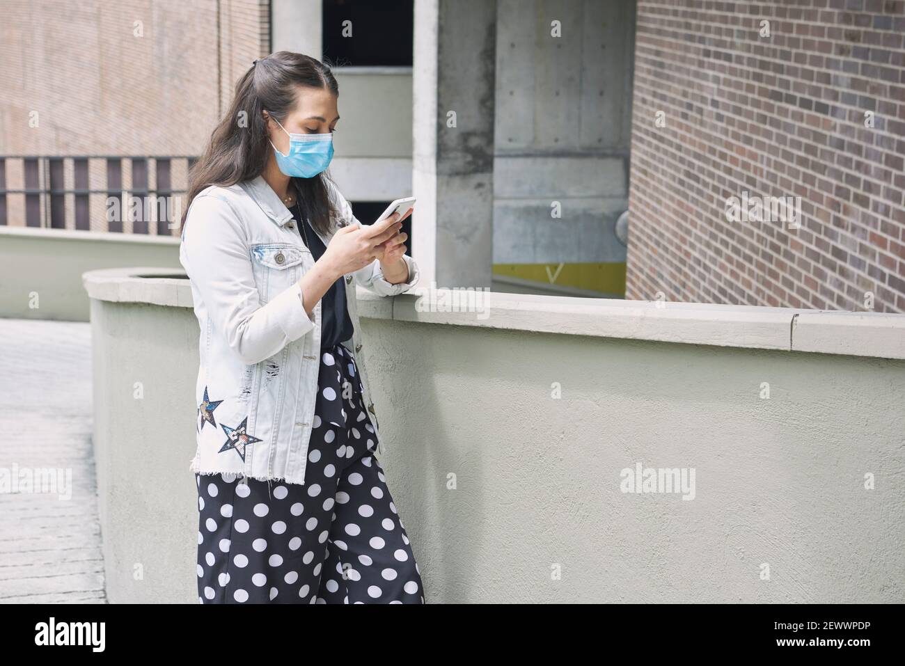 Une femme hispanique attirante dans un masque facial qui marche à l'intérieur un extérieur - Banque D'Images