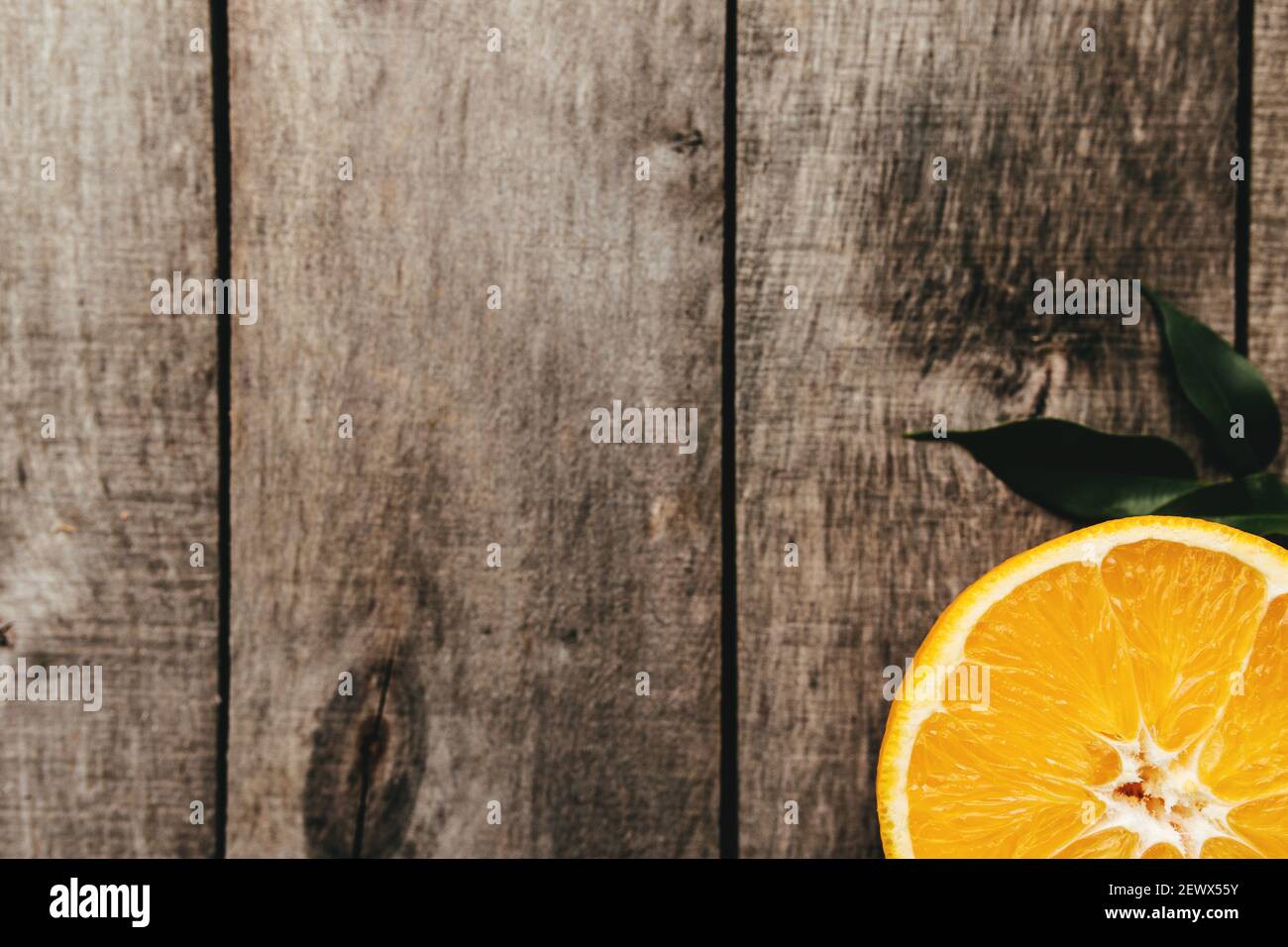 Tranches de fruits orange sur fond de bois gris. Pulpe et feuilles vertes. Photo de haute qualité Banque D'Images