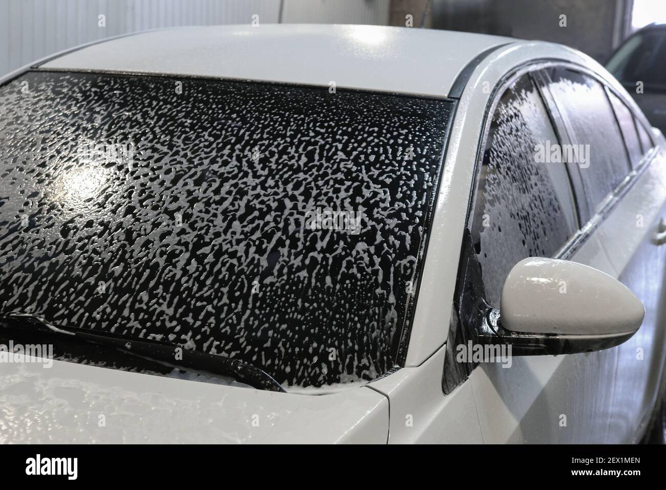 voiture moderne blanche recouverte de mousse dans le lavage de voiture Banque D'Images