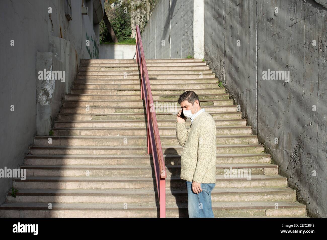 Homme travaillant au bureau pendant la période pandémique. Moyens d'être protégé de Covid19. Temps de pause à l'extérieur. Avec masque. Escaliers téléphoniques parlants, étape Banque D'Images