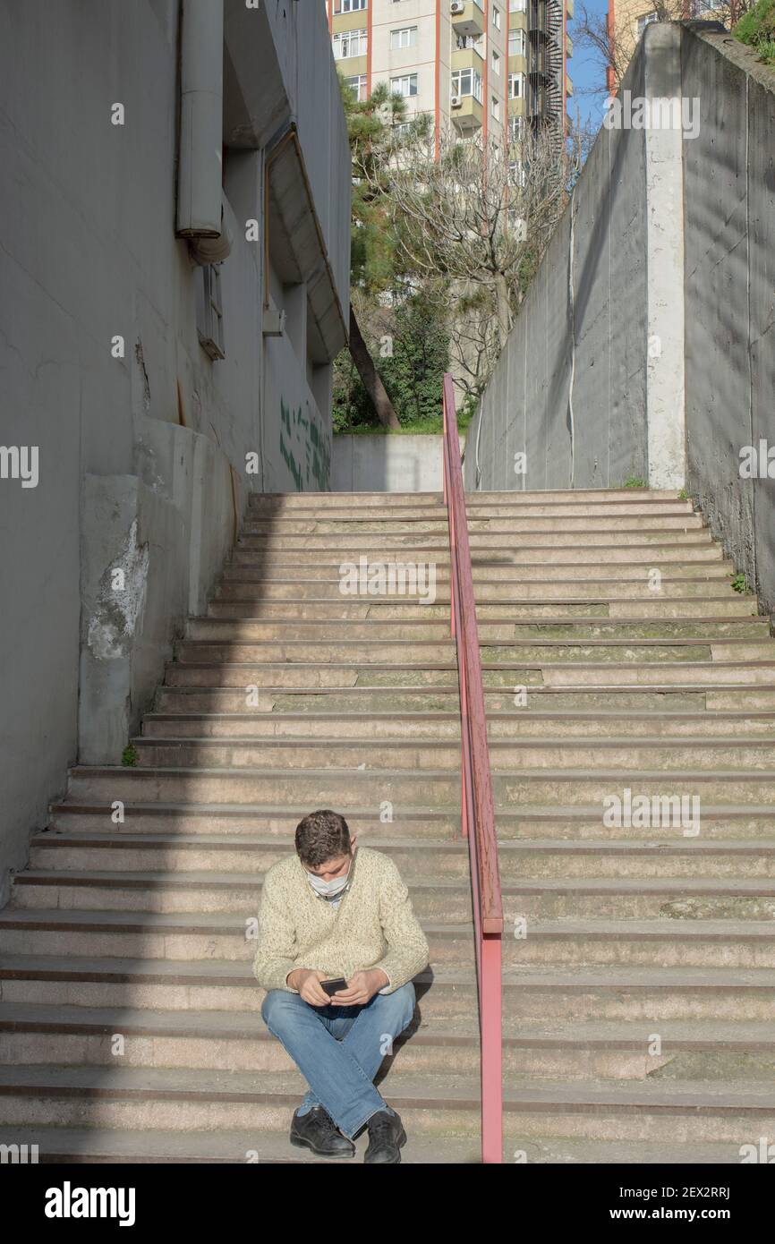 Homme travaillant au bureau pendant la période pandémique. Moyens d'être protégé de Covid19. Temps de pause à l'extérieur. Avec masque. Escaliers téléphoniques parlants, étape Banque D'Images