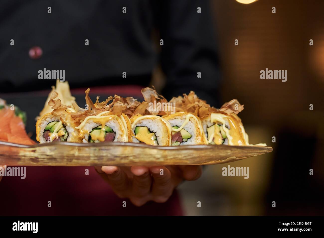 Fragmenter la photo de l'assiette avec de savoureux sushis avocat sur un plaque dans les mains du serveur Banque D'Images