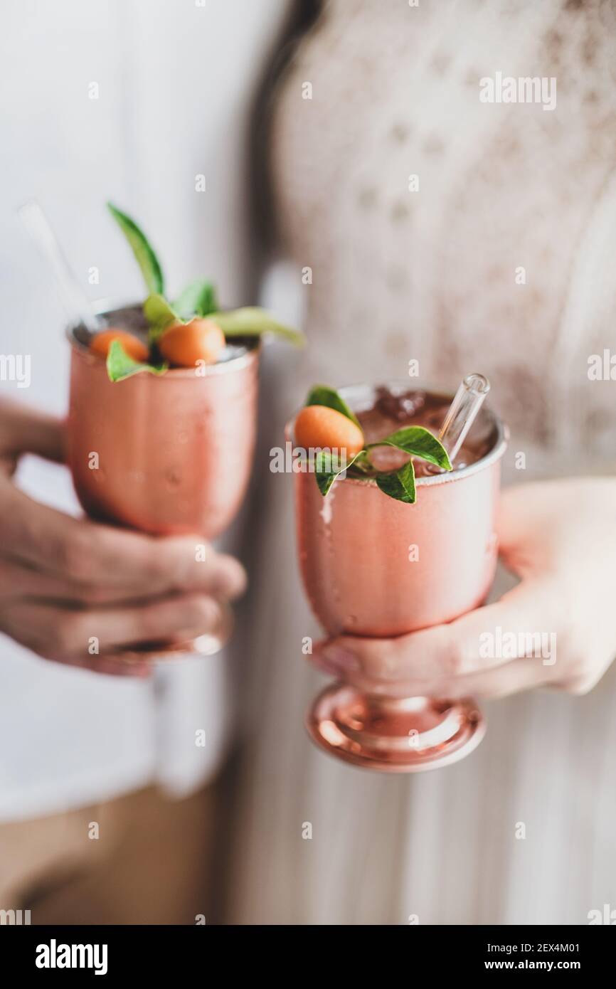 Des Mains De Couple Amoureux Celebrant Des Vacances Avec Un Cocktail De Glace Avec Des Agrumes En Gobelets En Laiton Et Des Pailles Ecologiques En Verre Ensemble En Gros Plan Anniversaire De