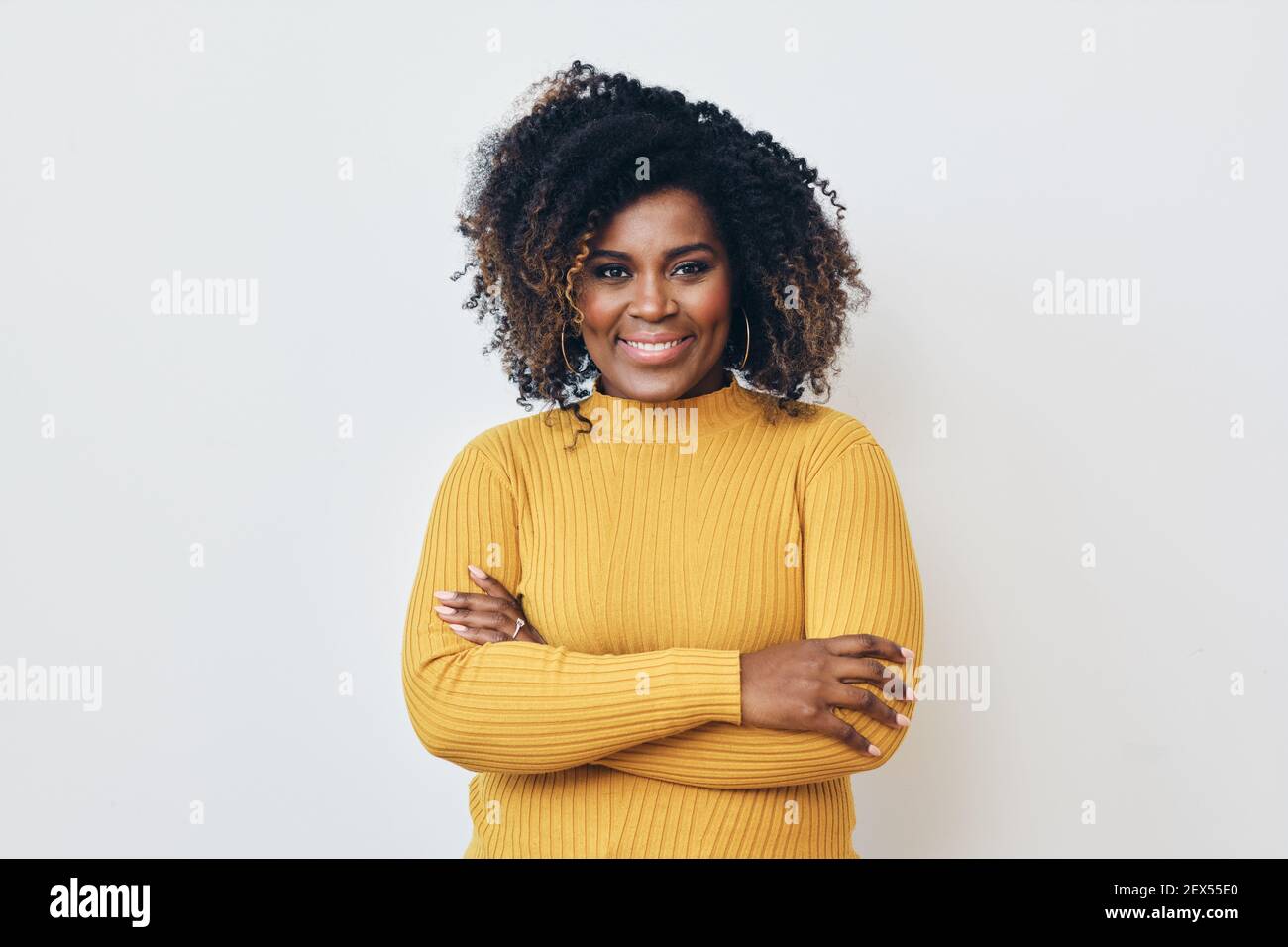 Portrait d'une belle femme noire souriant avec les bras croisés Banque D'Images