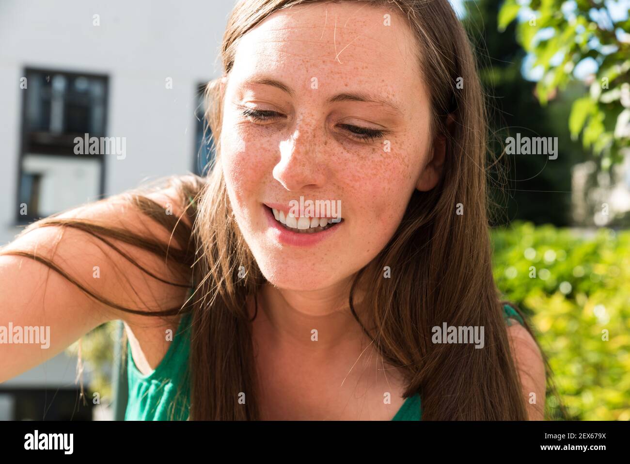 Portrait d'une jolie femme de trente ans, souriant au soleil sur sa terrasse en été Banque D'Images