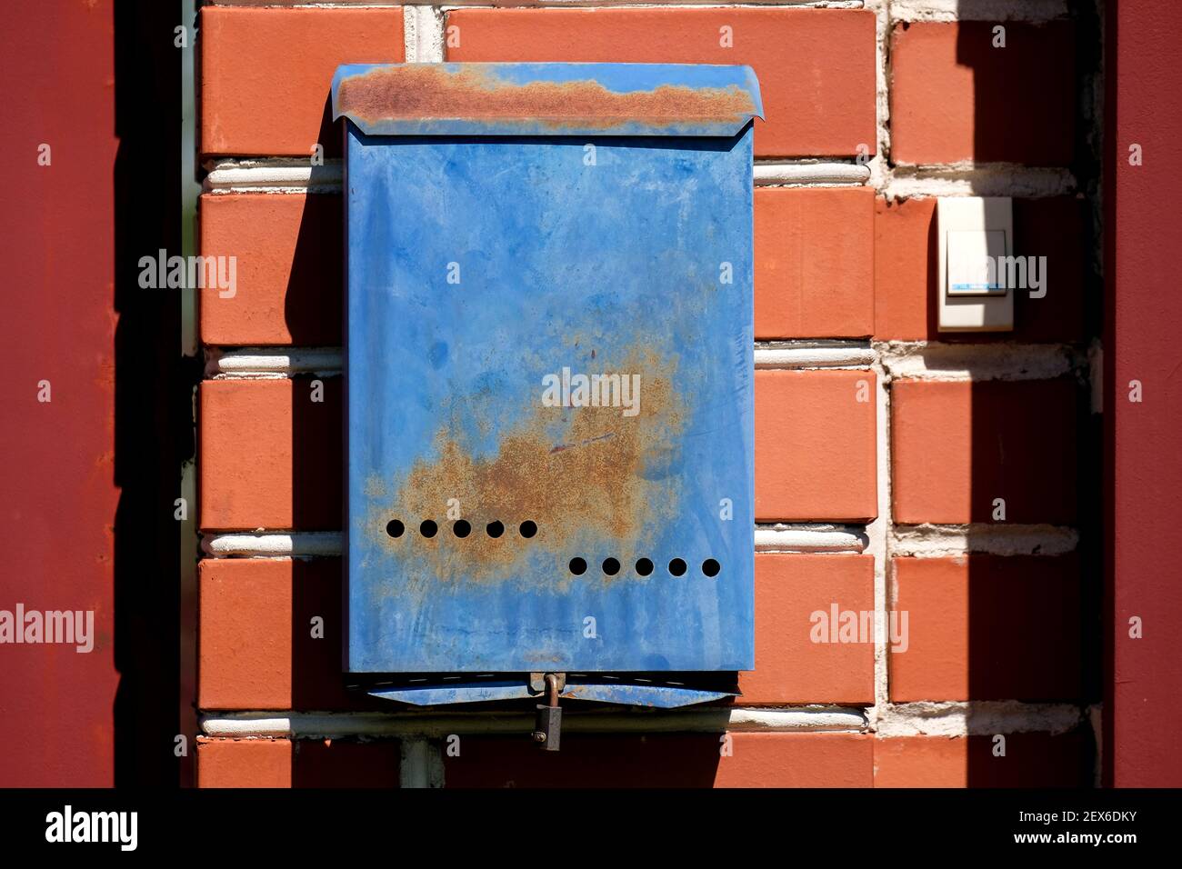 Une boîte aux lettres bleue est suspendue sur un mur de briques rouges à l'extérieur. Boîte postale russe. Banque D'Images