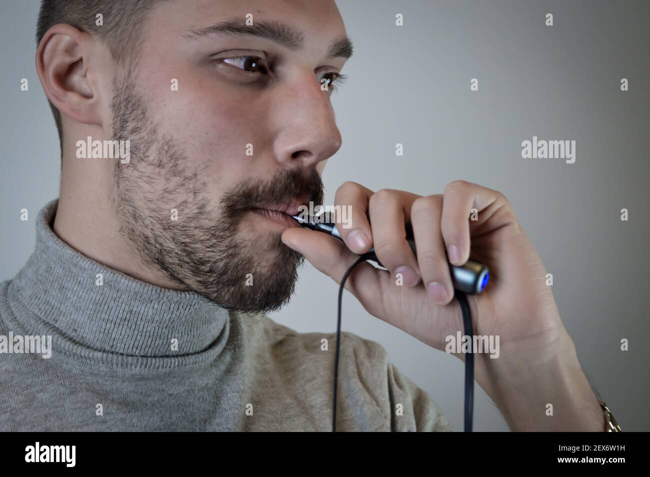 Portrait d'un jeune barbu qui fume une cigarette électronique, gros plan Banque D'Images