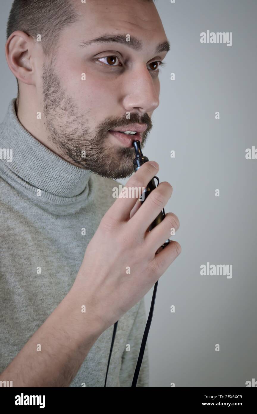 Portrait d'un jeune barbu qui fume une cigarette électronique, gros plan Banque D'Images