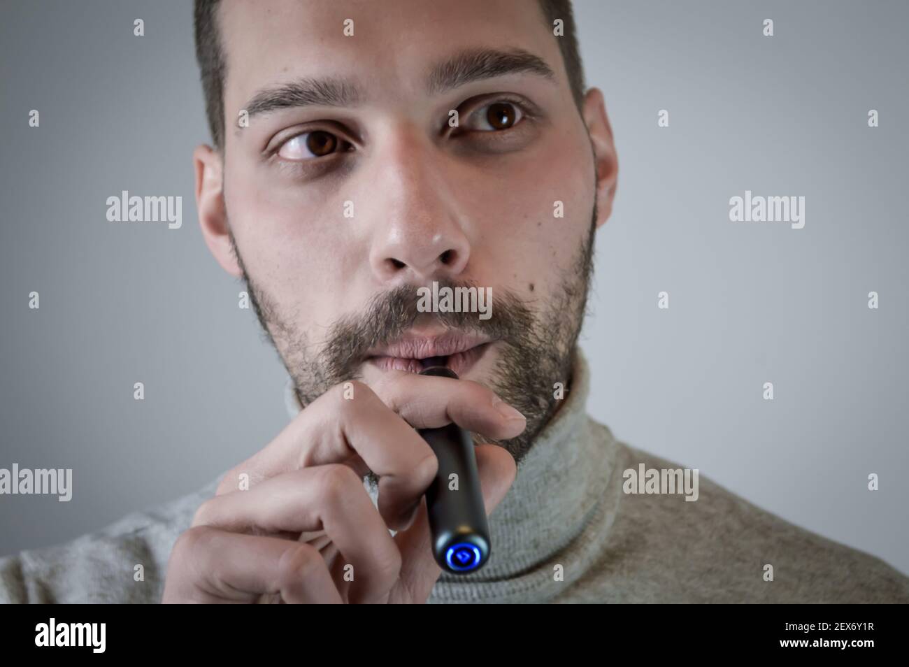 Portrait d'un jeune barbu qui fume une cigarette électronique, gros plan Banque D'Images