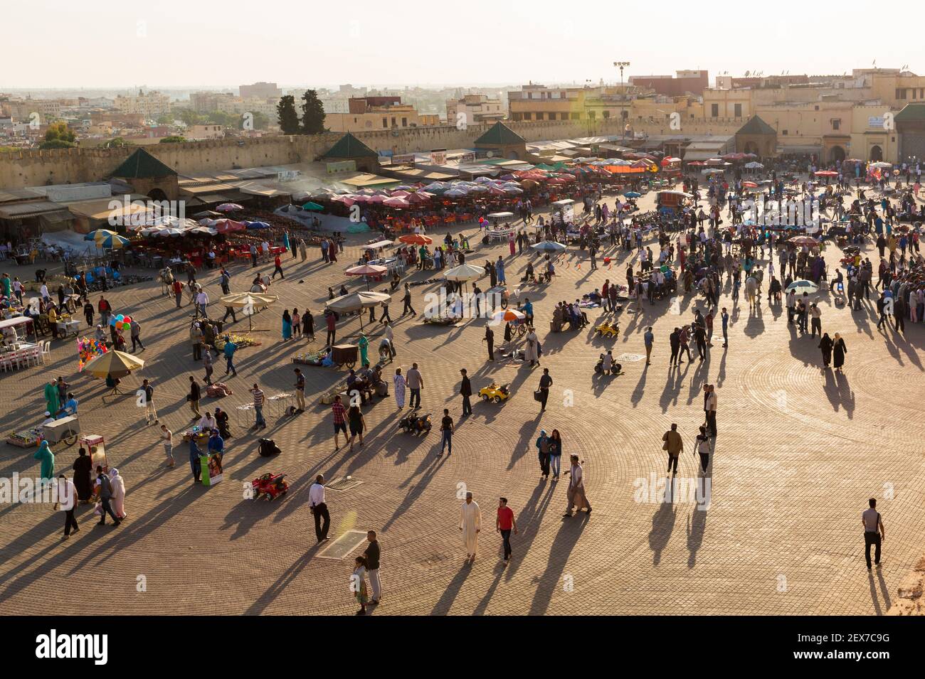 Maroc, Meknès, place el-Hedime, les gens se rassemblent au coucher du soleil sur une place, projetant de longues ombres. Banque D'Images