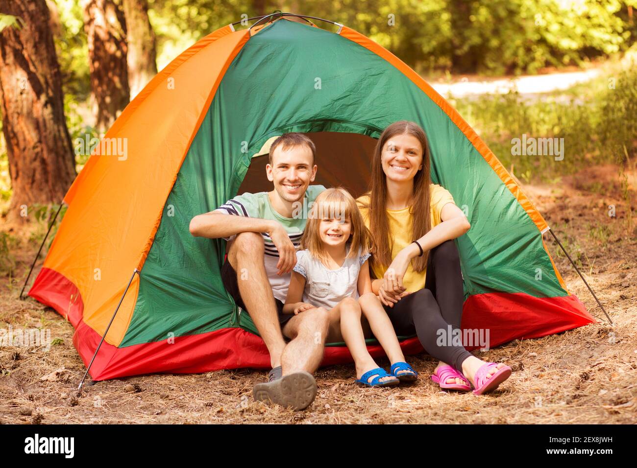 Famille de trois personnes campant et ayant du plaisir ensemble dans la forêt d'été. Camping vacances. Banque D'Images