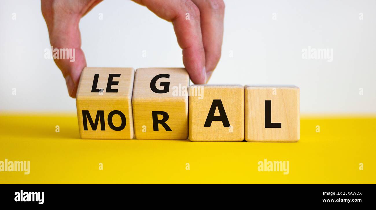 Symbole moral ou légal. La main d'homme d'affaires tourne des cubes en bois et change le mot « oral » en « legal » sur une belle table jaune, fond blanc. Busi Banque D'Images