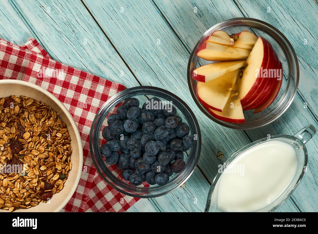 Le bol de granola, de bleuets et une tasse de lait sur fond de bois bleu. Banque D'Images