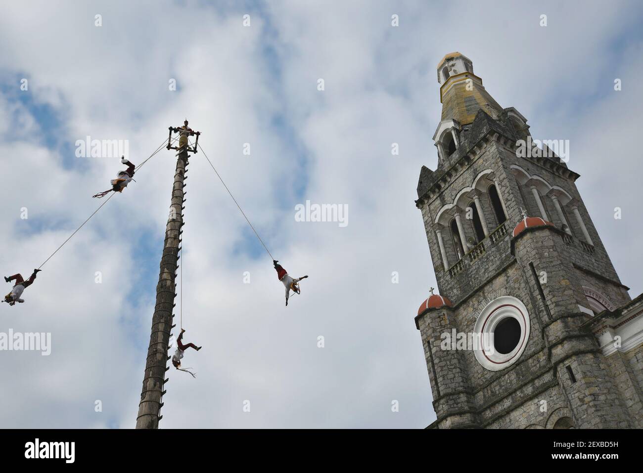 Danseurs qui exécutent le rituel de la danse des Flyers autour du poteau d'arbre de 30 mètres devant la Parroquia de San Francisco de Asís à Cuetzalan, Mexique. Banque D'Images