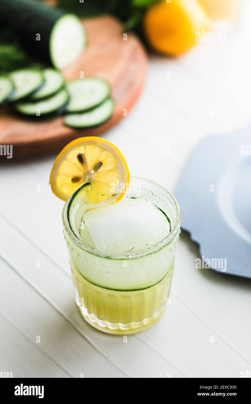 Boisson jaune-vert dans un verre rocailleux garni de concombres et citron Banque D'Images