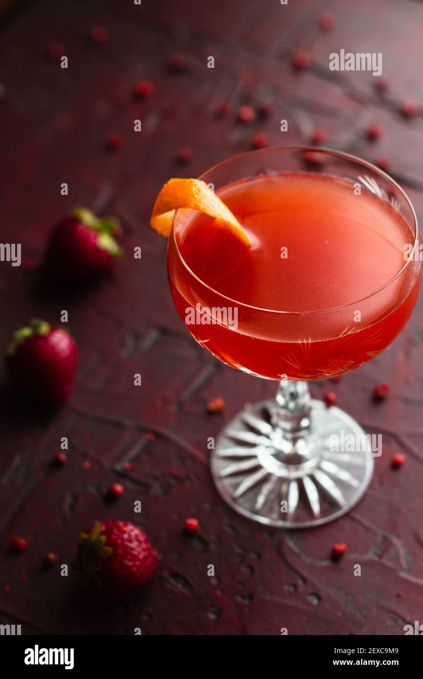 Cocktail de gin aux fraises dans un verre coupé vintage entouré de fraises  et de grains de poivre rose sur une surface rouge Photo Stock - Alamy